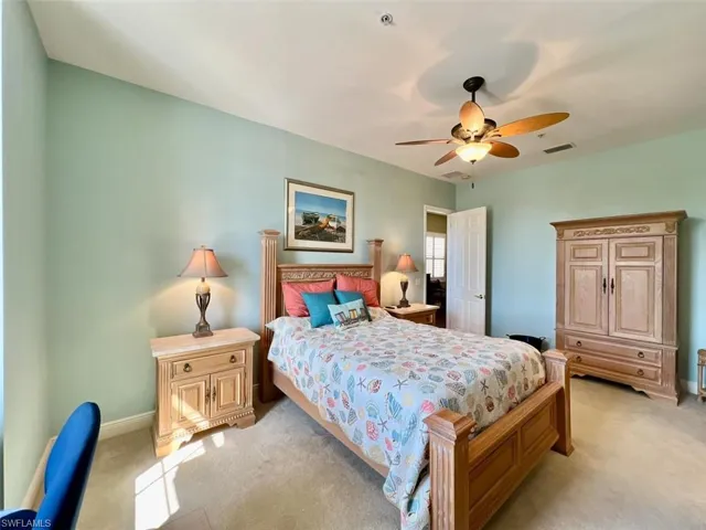 Guest master Bedroom with light colored carpet and ceiling fan