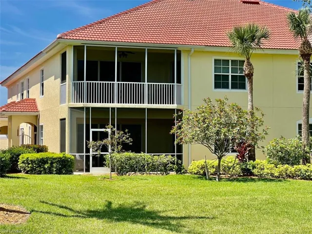 Back of property with a balcony and a yard