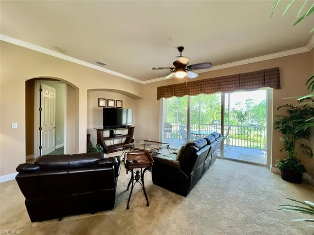 Carpeted living room featuring ceiling fan and ornamental molding
