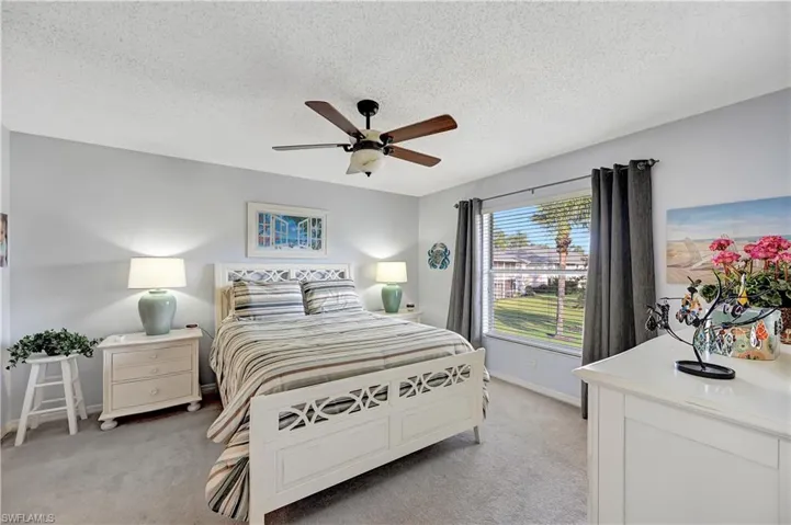 Bedroom with light carpet, ceiling fan, a textured ceiling, and baseboards