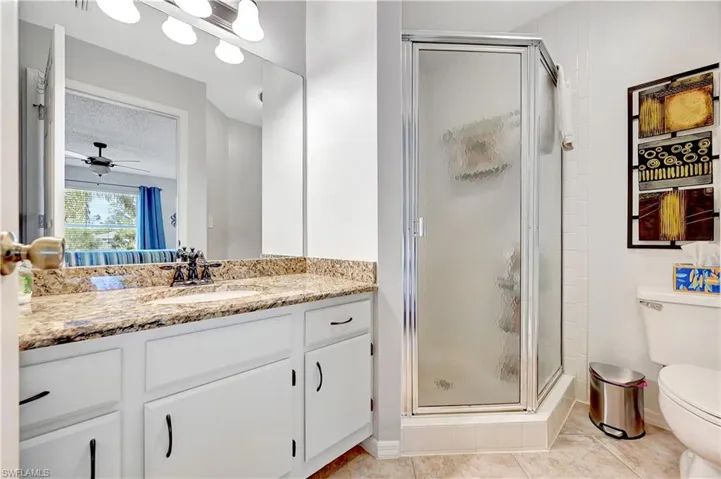 Bathroom with toilet, a stall shower, vanity, a textured ceiling, and tile patterned flooring