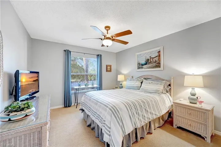 Bedroom featuring a textured ceiling, light carpet, a ceiling fan, and baseboards