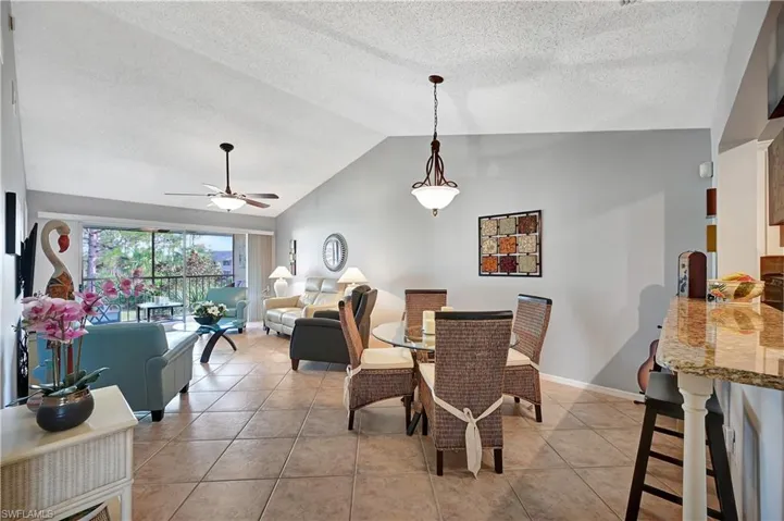 Dining room with ceiling fan, vaulted ceiling, baseboards, and light tile patterned floors