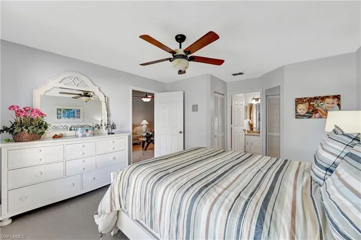Bedroom featuring carpet floors, visible vents, connected bathroom, and ceiling fan