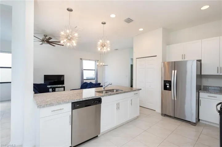 Kitchen with ceiling fan with notable chandelier, white cabinetry, appliances with stainless steel finishes, and sink