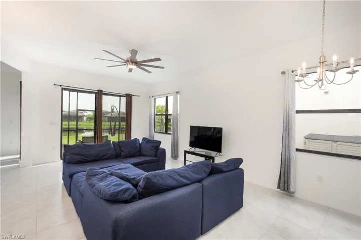 Tiled living room featuring ceiling fan with notable chandelier