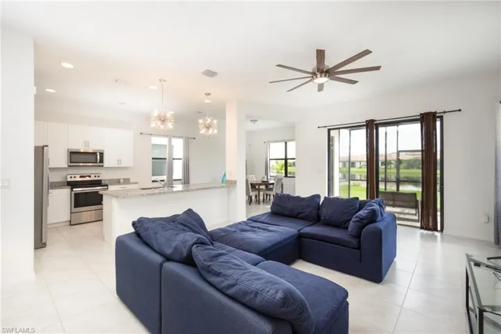 Living room with ceiling fan with notable chandelier and light tile patterned floors