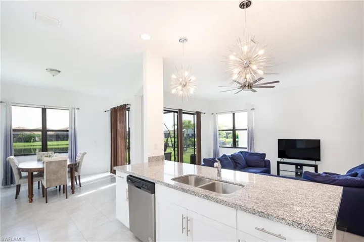 Kitchen with white cabinets, hanging light fixtures, sink, dishwasher, and ceiling fan with notable chandelier