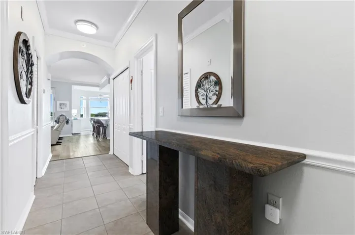 Corridor featuring arched walkways, crown molding, and light tile patterned flooring