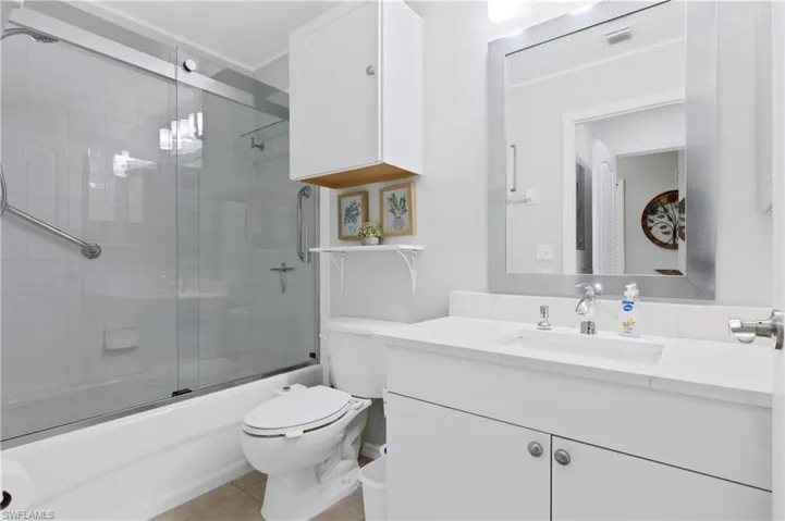 Full bathroom with vanity, bath / shower combo with glass door, and light tile patterned flooring