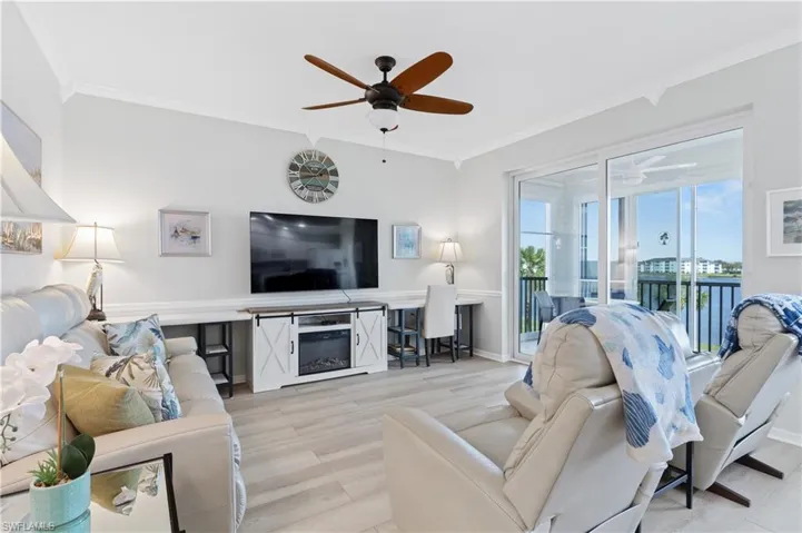 Living room with a ceiling fan, light wood-style flooring, and crown molding