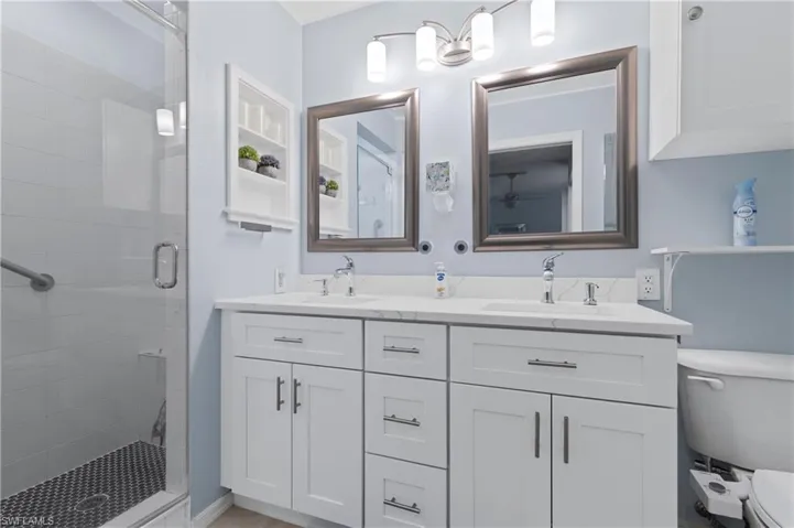 Full bathroom with double vanity and a shower stall