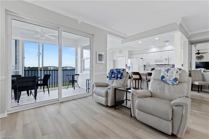 Living area featuring a ceiling fan, a water view, light wood-style floors, crown molding, and recessed lighting