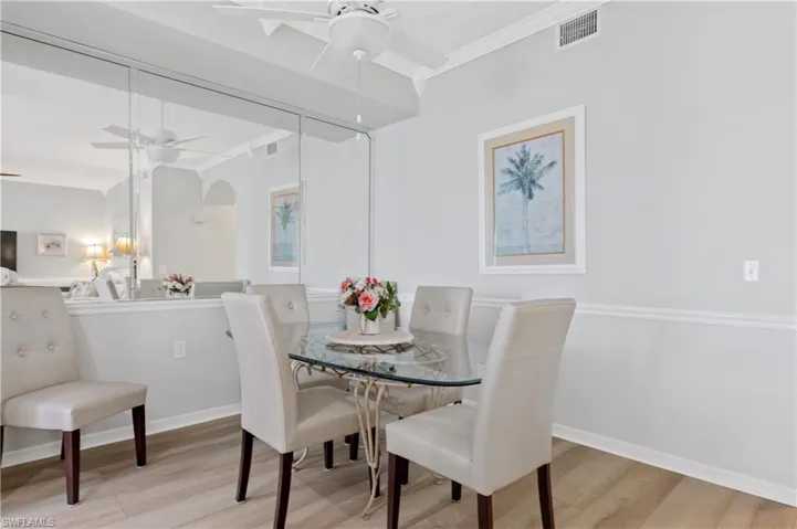 Dining space with ornamental molding, light wood finished floors, and ceiling fan