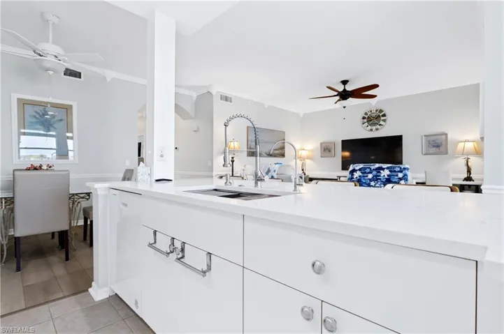 Kitchen with ceiling fan, open floor plan, white cabinets, and dishwasher