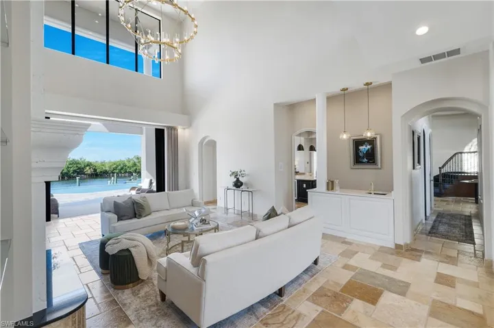 Living room with stone tile flooring, hanging lights, a high ceiling, and arched walkways