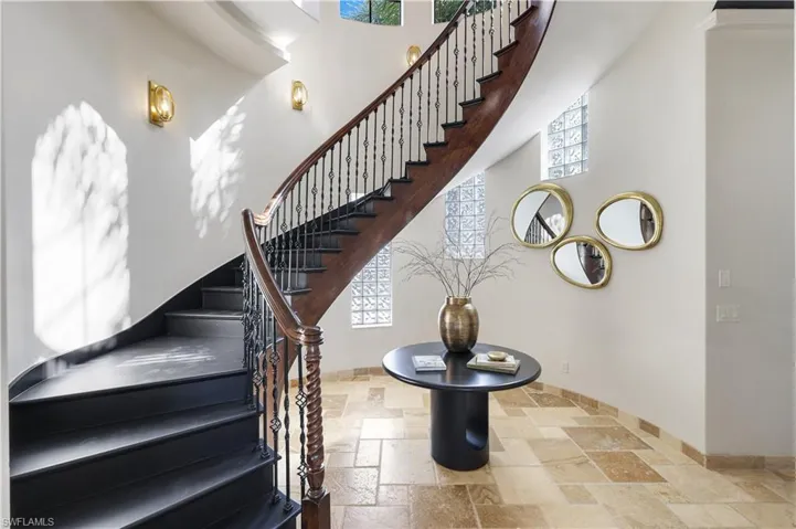 Stairway featuring stone tile floors and a high ceiling