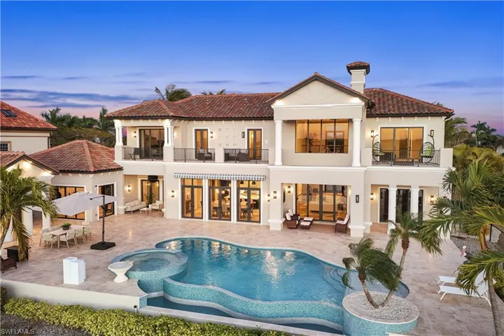 Rear view of property with outdoor dining area, a pool with connected hot tub, a tile roof, stucco siding, and a balcony