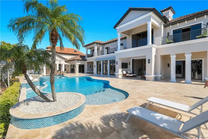 Back of house featuring a balcony, stucco siding, a patio, a pool with connected hot tub, and a tile roof