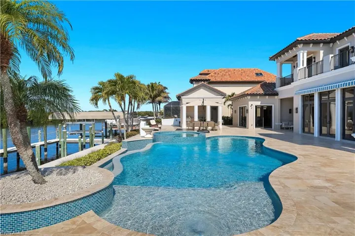 Integrated pool / hot tub with a patio area, boat lift, a dock, and a balcony