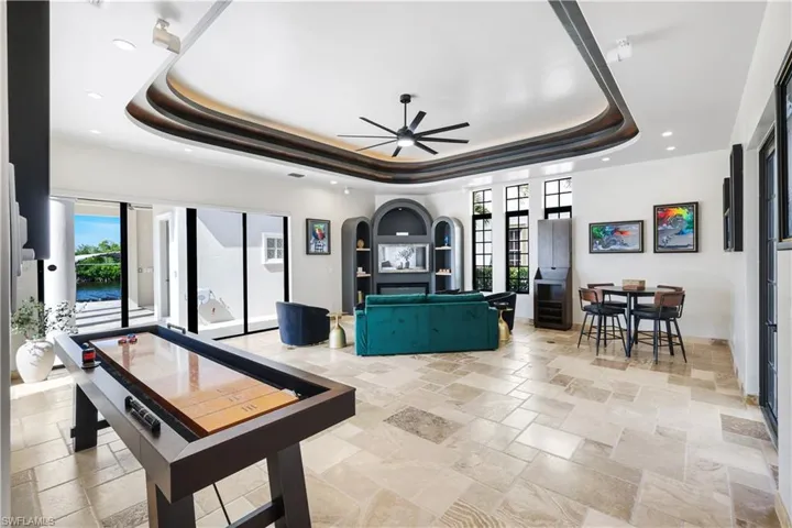 Rec room with stone tile flooring, a ceiling fan, recessed lighting, and arched walkways