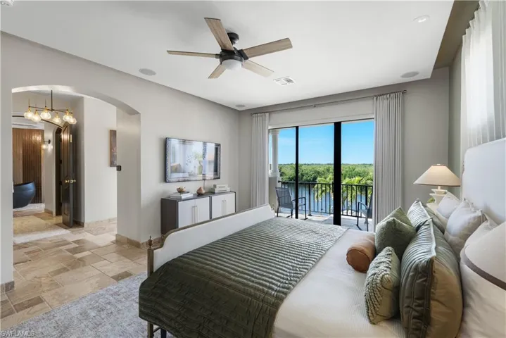 Bedroom featuring stone tile flooring, access to outside, arched walkways, and ceiling fan