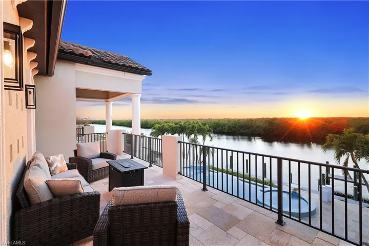 Balcony at dusk featuring a patio, an outdoor living space with a fire pit, and a water view