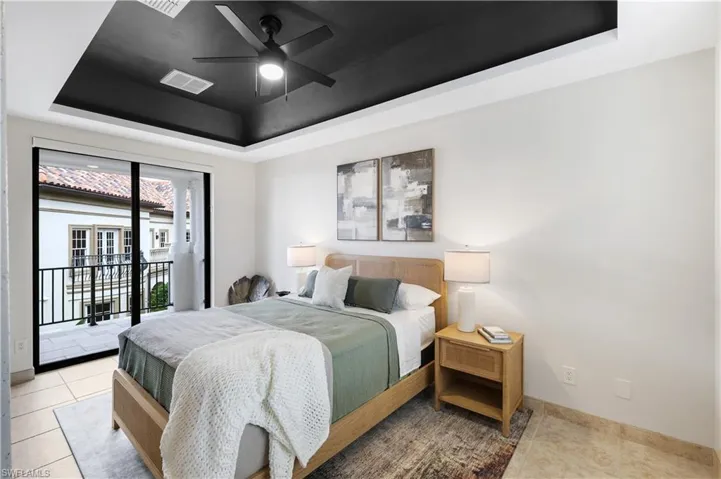 Bedroom with a raised ceiling, access to exterior, a ceiling fan, and tile patterned floors