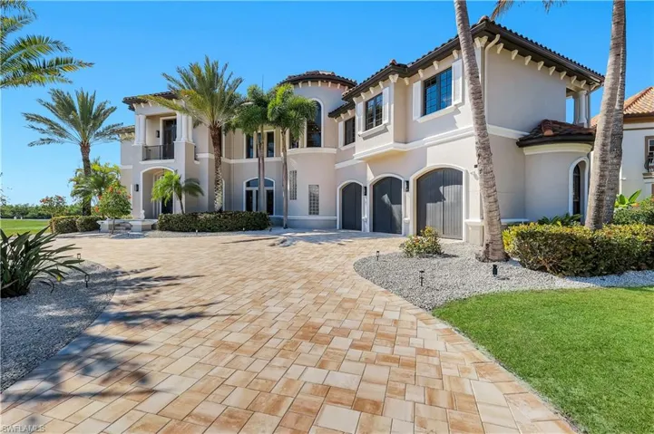 Mediterranean / spanish-style home with a garage, stucco siding, driveway, and a front lawn