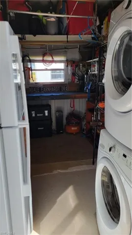 Shed featuring stacked washer and dryer and extra refrigerator/freezer for convenience, workbench and shelving.