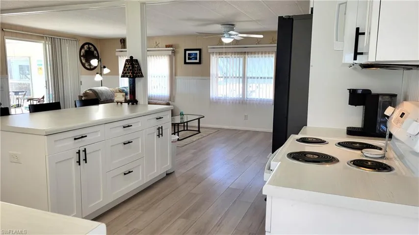 Kitchen featuring white cabinetry, light countertops, white range oven, light wood finished floors, and a wainscoted wall