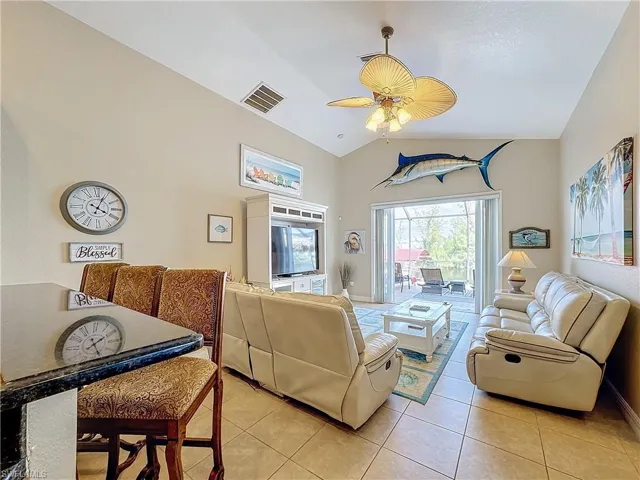 Living room with light tile patterned floors, ceiling fan, and vaulted ceiling