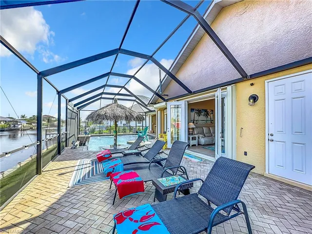 View of sun deck with screen enclosure, an outdoor pool, and a sunroom