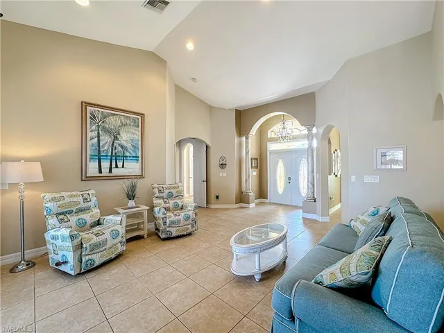 Living room with light tile patterned floors, lofted ceiling, and arched walkways