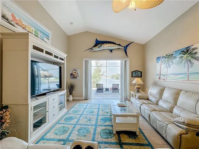 Living area featuring vaulted ceiling, ceiling fan, and light tile patterned floors