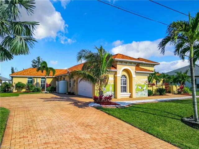 Mediterranean / spanish house with a front yard, stucco siding, decorative driveway, and a garage
