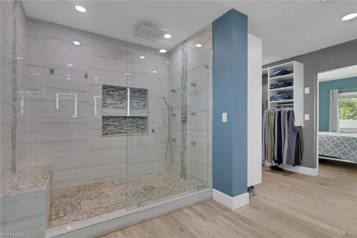 Full bathroom featuring ensuite bath, a stall shower, light wood-style floors, a spacious closet, and recessed lighting