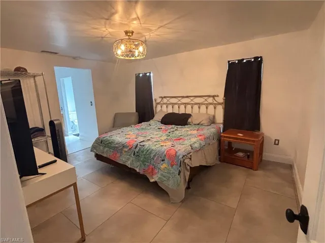 Bedroom with tile patterned flooring, a chandelier, and a wall mounted AC