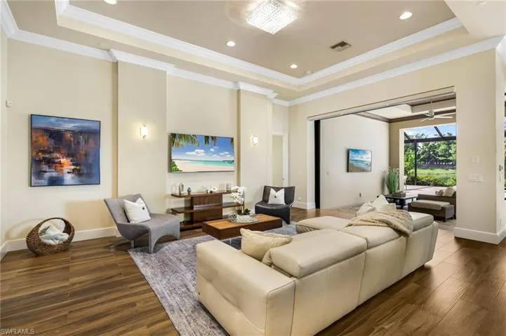 Living room with wood-type flooring, ceiling fan, and a tray ceiling
