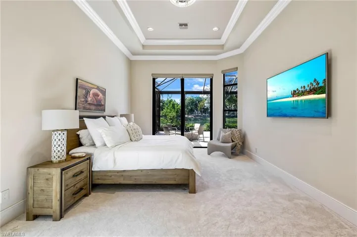 Bedroom with access to outside, ornamental molding, a tray ceiling, and carpet flooring