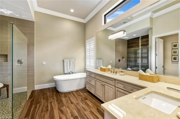 Bathroom featuring dual vanity, plus walk in shower, crown molding, and hardwood / wood-style flooring