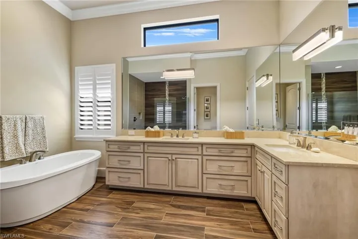 Bathroom with a tub, dual vanity, and crown molding