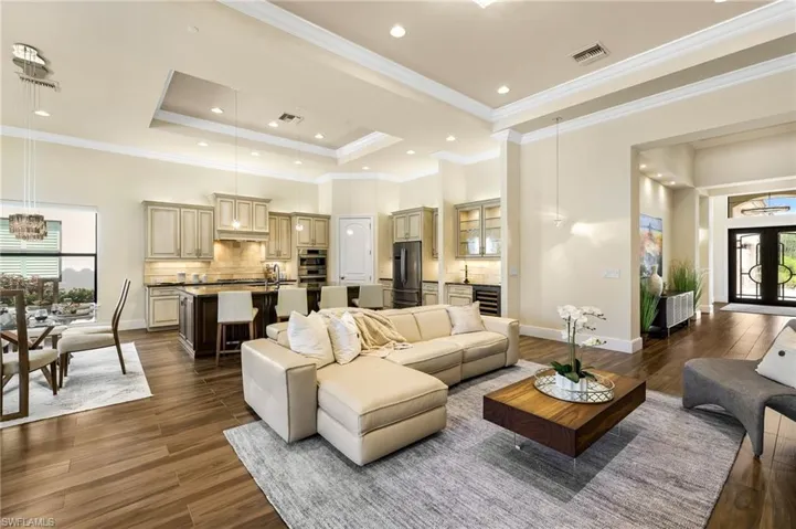 Living room featuring dark wood-type flooring, crown molding, wine cooler, and a tray ceiling