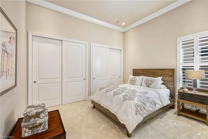 Bedroom with ornamental molding, multiple closets, and light colored carpet