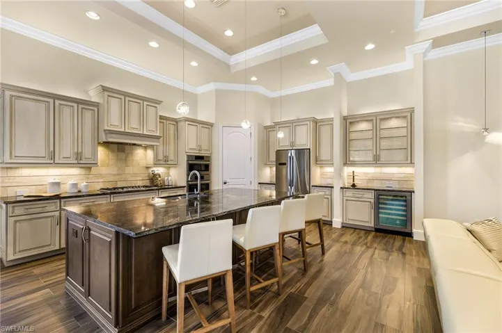 Kitchen featuring tasteful backsplash, dark stone countertops, appliances with stainless steel finishes, and an island with sink
