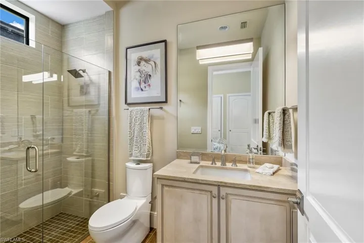 Bathroom with vanity, an enclosed shower, and toilet