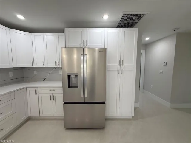 Kitchen with stainless steel fridge with ice dispenser, recessed lighting, white cabinets, and backsplash