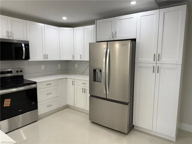 Kitchen with stainless steel appliances, white cabinetry, recessed lighting, and backsplash