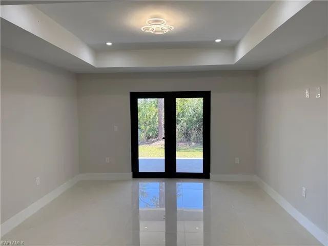 Empty room featuring a raised ceiling, french doors, and recessed lighting