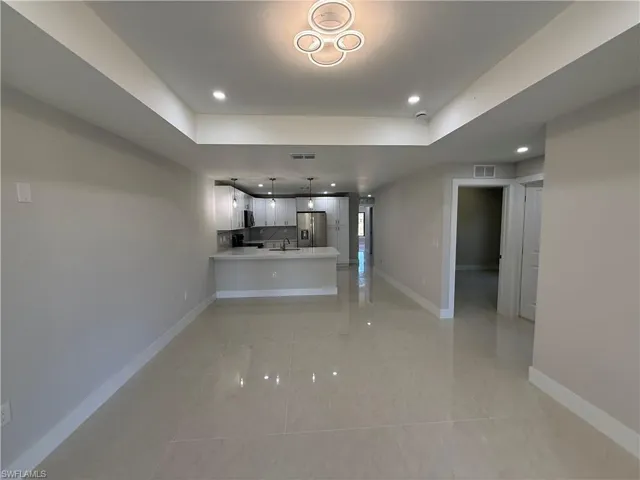 Unfurnished living room with recessed lighting and a raised ceiling
